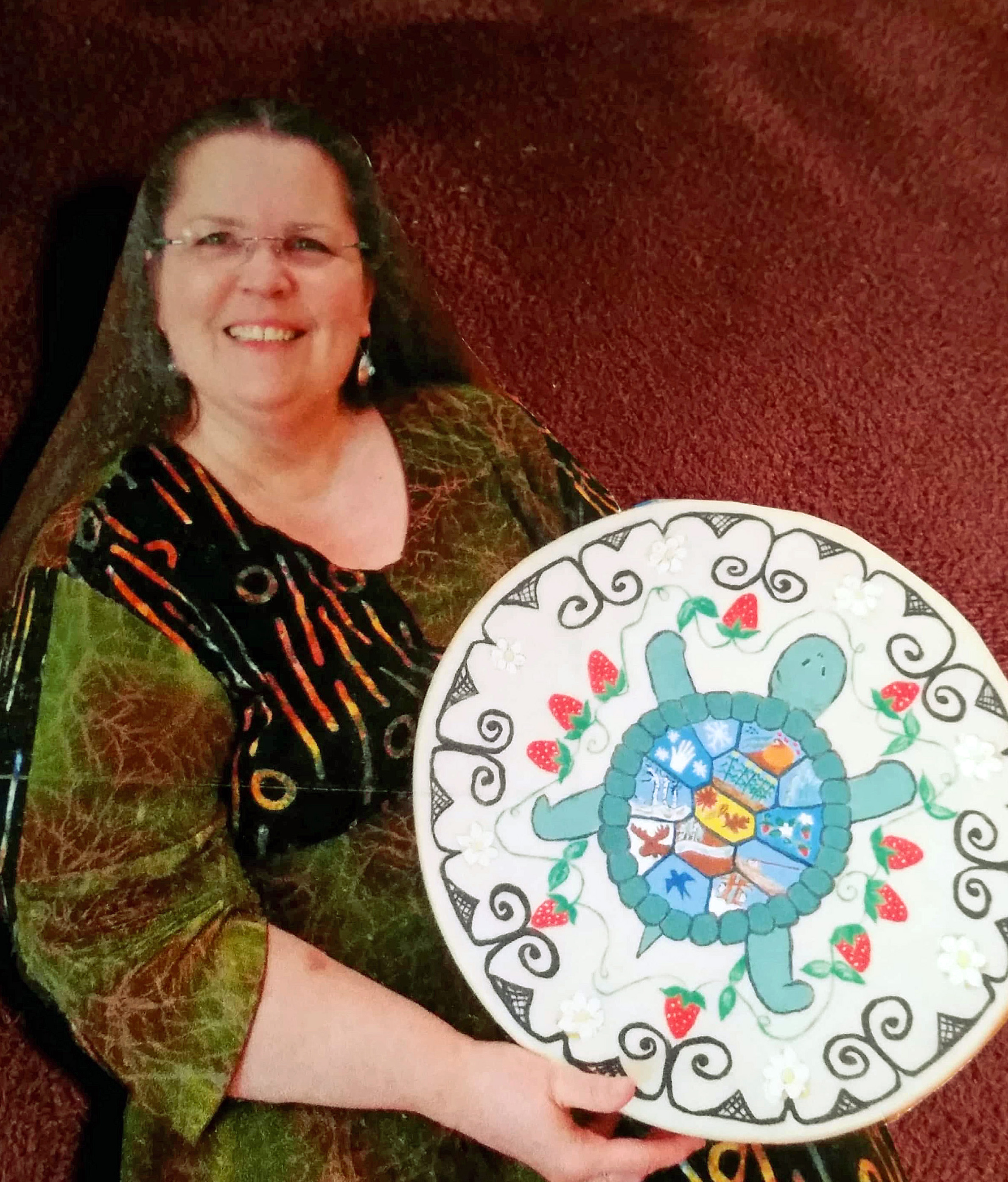 Portrait of Anne Jennison holding a traditional painted Tolba, or turtle, drum. 