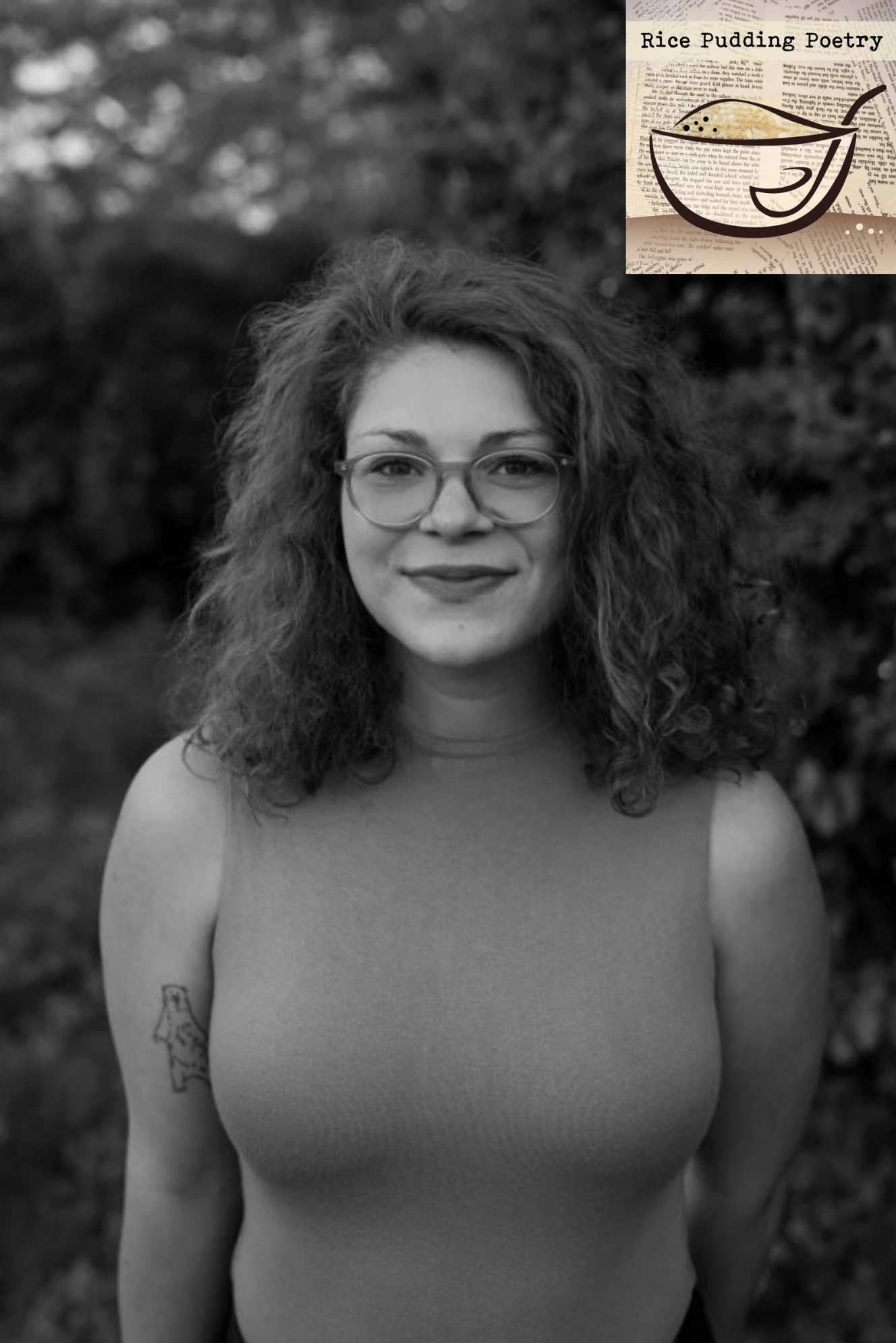 Poet Lily Greenberg faces the camera, wearing glasses and smiling in an outdoor setting with trees behind her; she wears a sleeveless shirt and a tattoo of a bear is visible on one arm; the photo is in black and white. The Rice Pudding Poetry logo is in the upper right corner--a cartoon bowl of rice pudding with a spoon, in front of book pages.