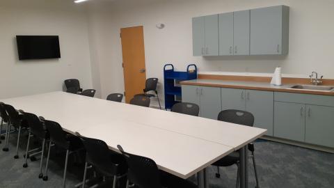 Image of the center table, cabinets, sink, and wall-mounted television of the Makerspace.