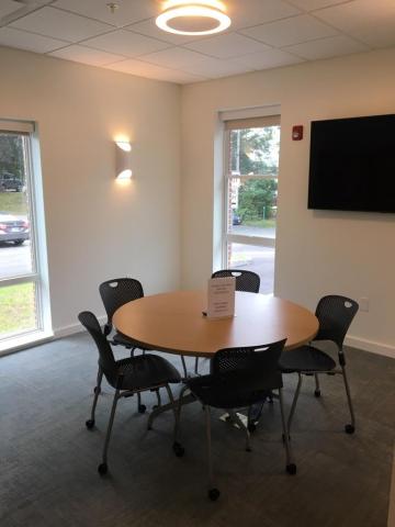 Image of the table with 5 chairs, and the wall-mounted television.