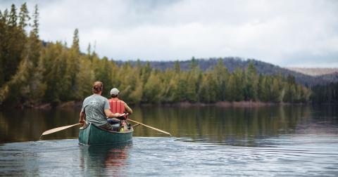 Image of two people in a green canoe paddling down the Allagash River.