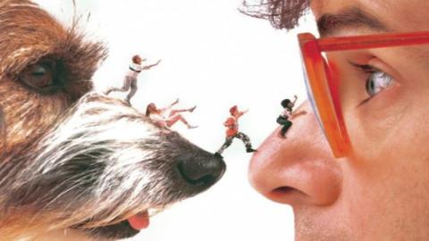 Movie poster for Honey, I Shrunk the Kids. Four shrunken kids walk across the snout of a dog to the nose of their father.