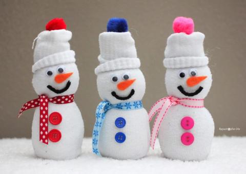 three snowmen made out of white socks, decorated with felt and buttons