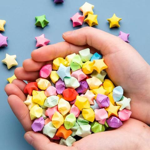 Several multicolors origami paper stars cupped in hands