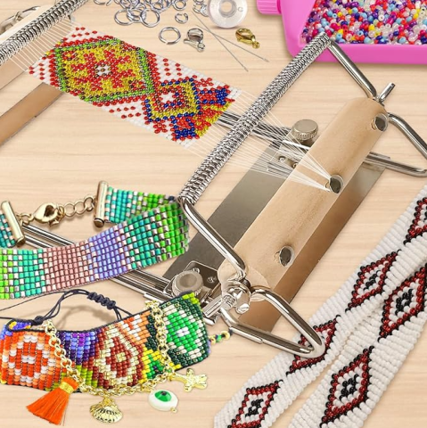 Photo of a bead loom on a table with a colorful pattern partially completed. Other beaded straps are on the table.