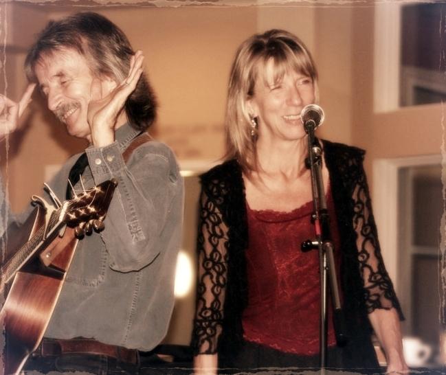 Image of Jenn and Kurt performing. Kurt is playing guitar and Jenn is singing.