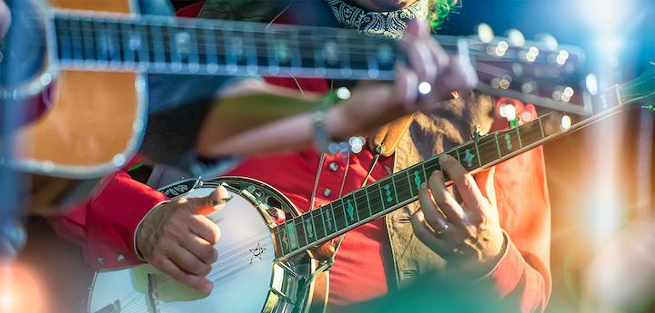 Photo of men playing guitars and banjos.