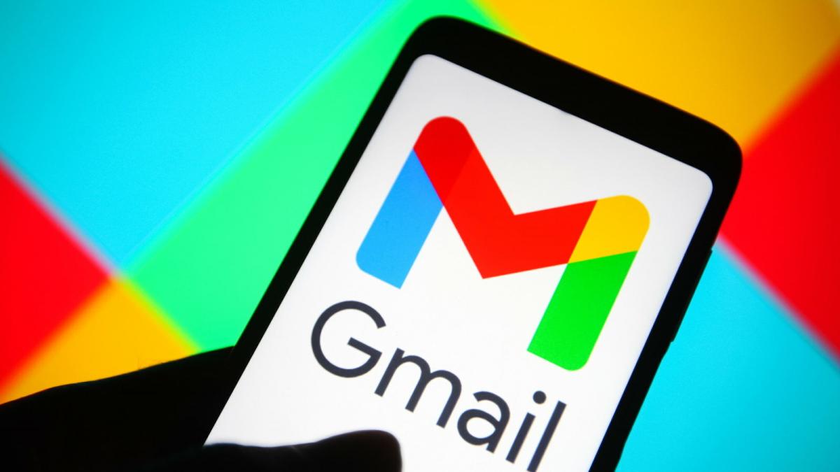 A smartphone displays the Gmail app against a multicolored background.