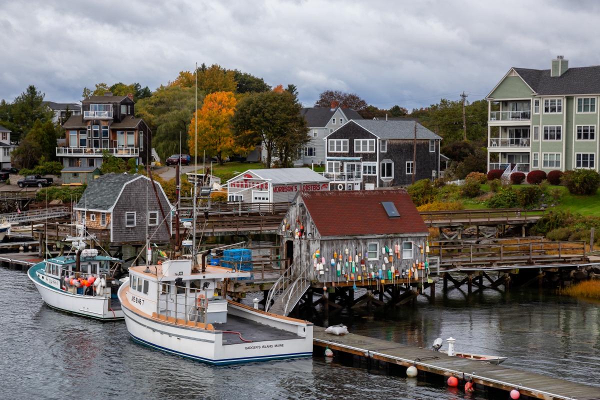 Kittery town pier. Several lobster boats are in the water with homes and churches in the background